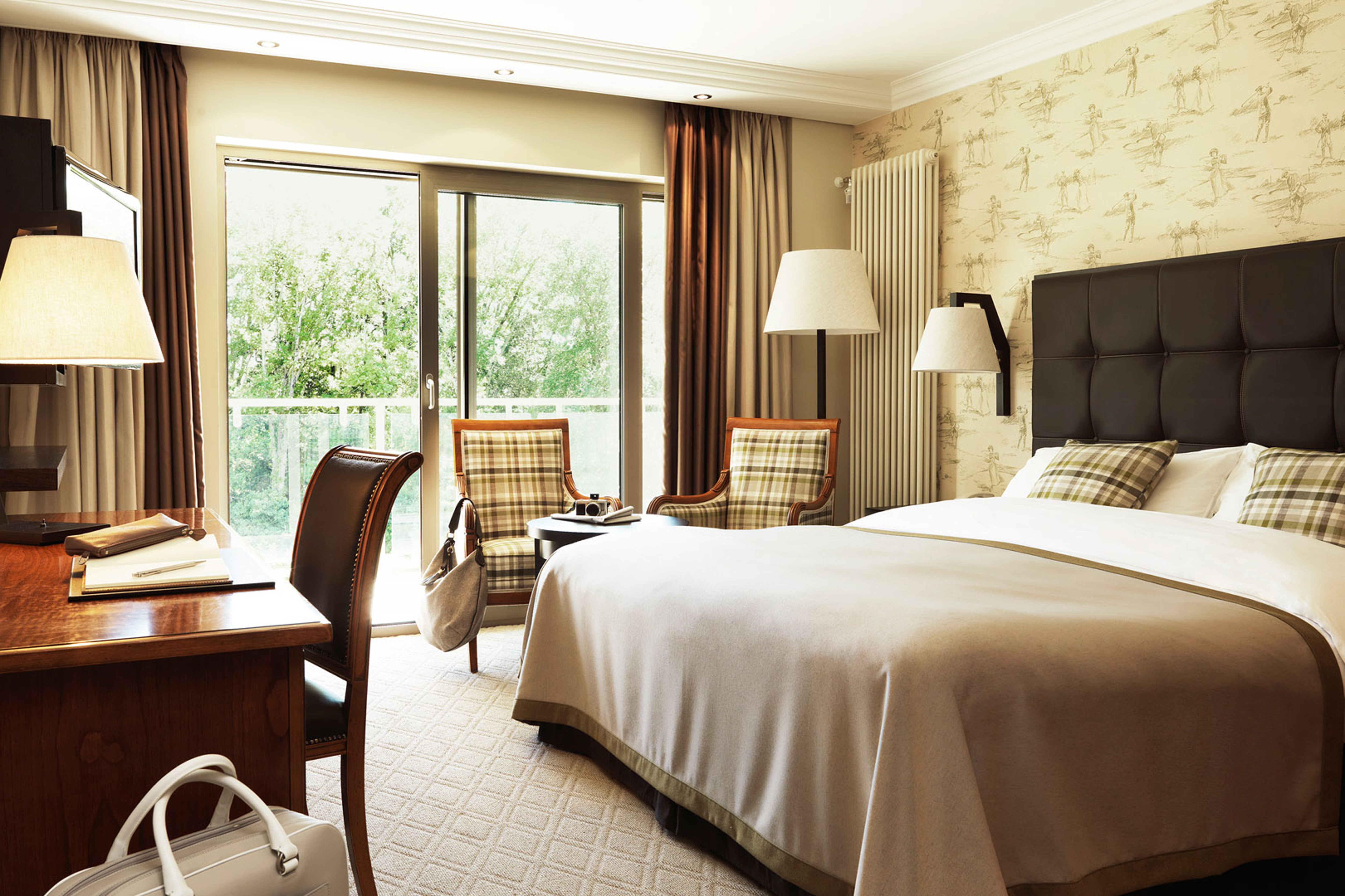 Room of a hotel with bed, table, lamp and chairs